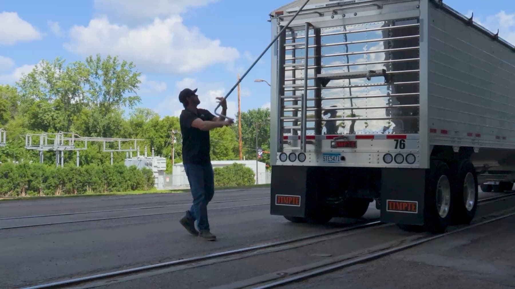 Driver tarping a hopper bottom trailer